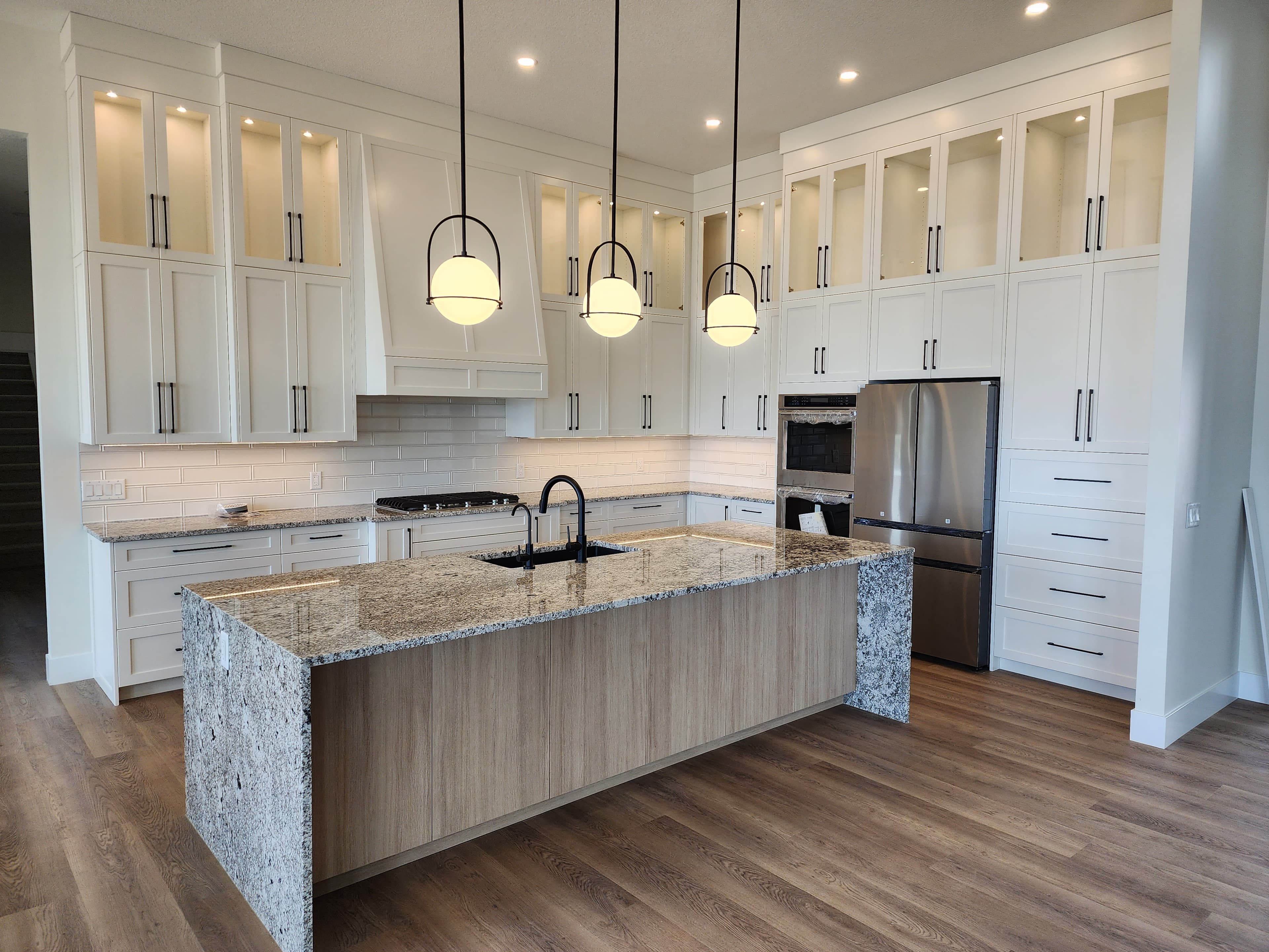 Gordon residence — white cabinets with gray island, Wolf range, and pendant lights by Columbia Carpentry